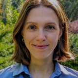 Photo de profil de Natalia Ladyka-Wojcik, vêtue d'une chemise bleue sur fond vert.