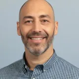 Une photo de Ivo Pessanha portant une chemise avec des petits quadrillés bleu et blanc. 