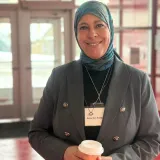 Aziza Louati tenant une tasse de café lors d’un événement.
