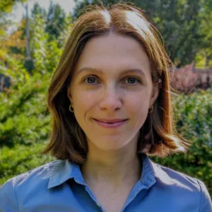 Photo de profil de Natalia Ladyka-Wojcik, vêtue d'une chemise bleue sur fond vert.