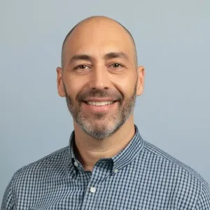 Une photo de Ivo Pessanha portant une chemise avec des petits quadrillés bleu et blanc. 