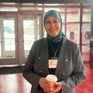Aziza Louati tenant une tasse de café lors d’un événement.